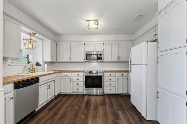 kitchen with visible vents, butcher block countertops, stainless steel appliances, dark wood-type flooring, and tasteful backsplash