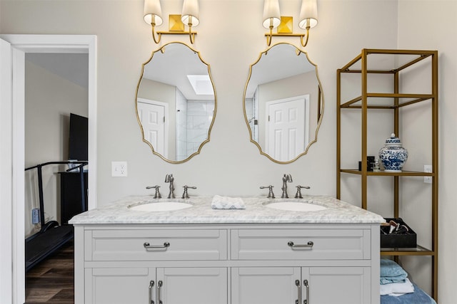 full bathroom with double vanity, wood finished floors, and a sink