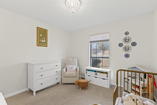 bedroom featuring baseboards, a crib, and carpet