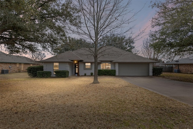 ranch-style house with central air condition unit, a front lawn, driveway, a shingled roof, and a garage