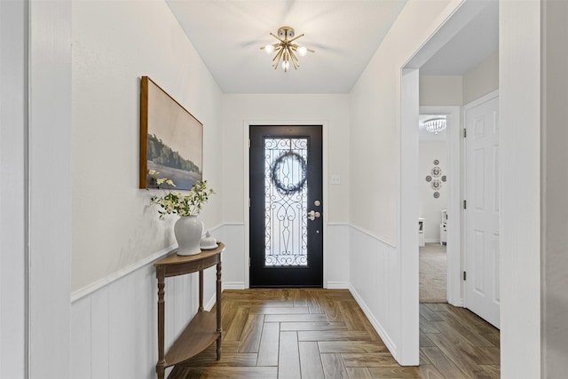 foyer featuring a chandelier and wainscoting