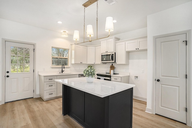 kitchen with light countertops, white cabinets, appliances with stainless steel finishes, and a sink