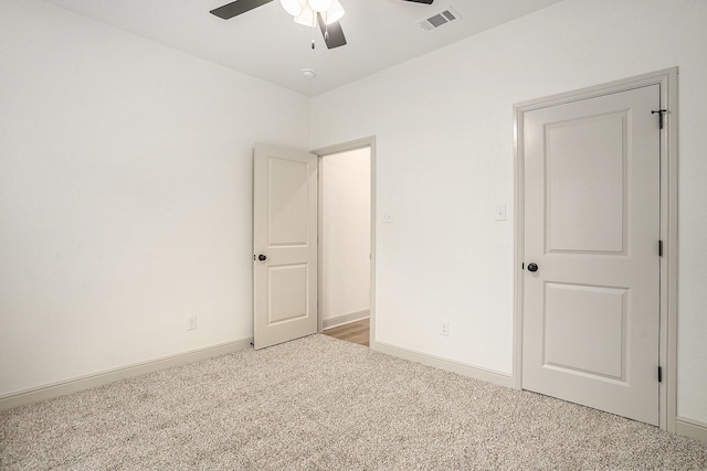 carpeted spare room with visible vents, ceiling fan, and baseboards