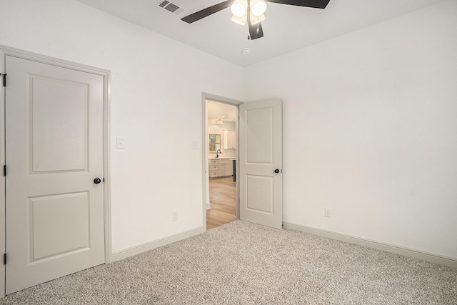 unfurnished bedroom with visible vents, light carpet, baseboards, and a ceiling fan