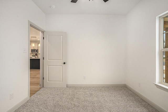 empty room featuring ceiling fan, baseboards, and carpet floors