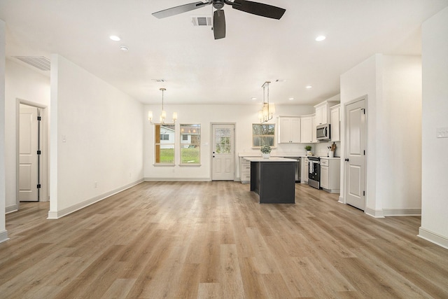 kitchen featuring light wood finished floors, open floor plan, stainless steel appliances, and light countertops