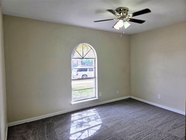 unfurnished room featuring a ceiling fan, baseboards, and dark carpet