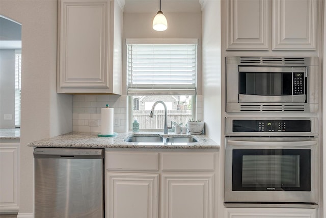 kitchen featuring a sink, light stone counters, white cabinetry, appliances with stainless steel finishes, and decorative backsplash