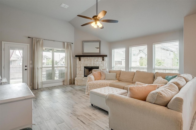 living area featuring light wood finished floors, visible vents, ceiling fan, a fireplace, and high vaulted ceiling