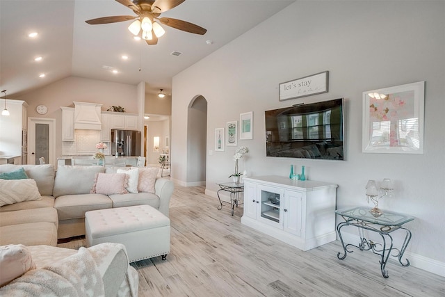 living area featuring baseboards, a ceiling fan, arched walkways, and light wood-type flooring