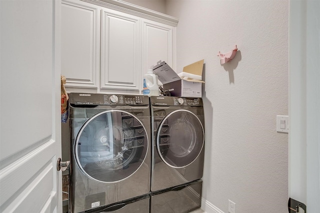 clothes washing area with a textured wall, cabinet space, and washing machine and clothes dryer