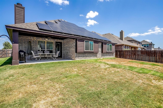 back of property featuring a patio, solar panels, a fenced backyard, a lawn, and brick siding