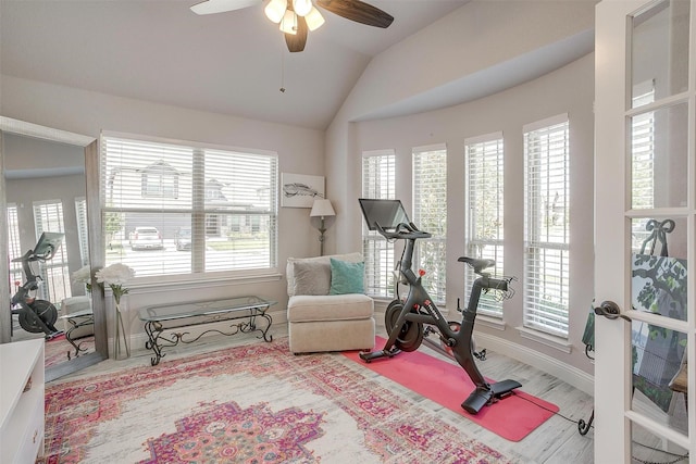 exercise area featuring lofted ceiling, a ceiling fan, and baseboards