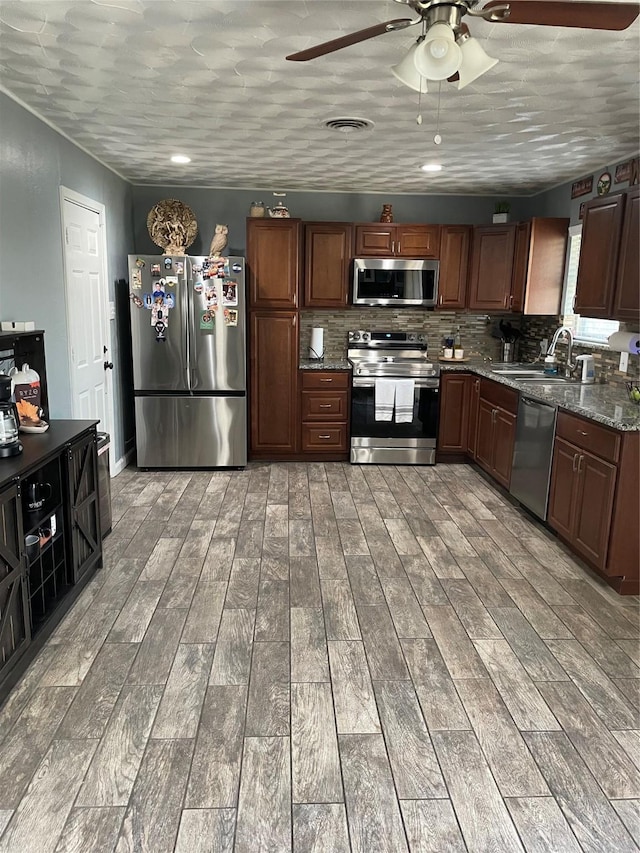 kitchen featuring visible vents, backsplash, light wood-type flooring, stainless steel appliances, and a sink