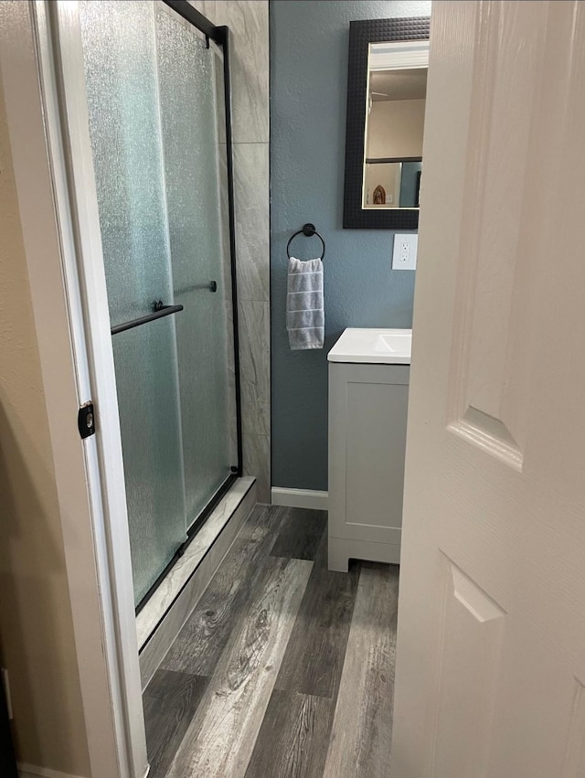 bathroom featuring vanity, wood finished floors, a shower stall, and a textured wall