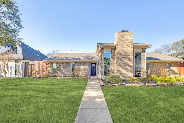 view of front of property featuring a front lawn, fence, and brick siding