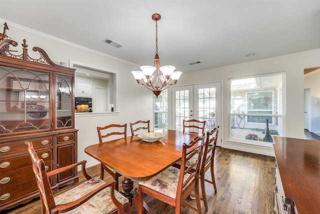 dining space with visible vents, wood finished floors, ornamental molding, and french doors