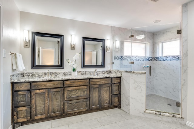 full bath featuring a marble finish shower, double vanity, and a sink