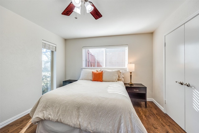 bedroom with dark wood-type flooring, baseboards, ceiling fan, and a closet
