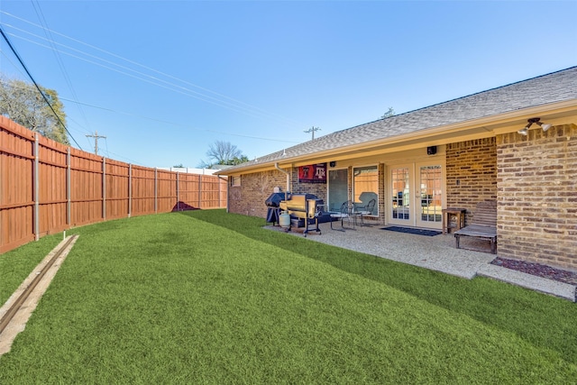 view of yard featuring a patio, a fenced backyard, and french doors