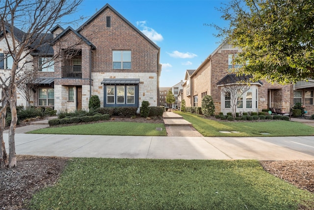 view of front of house featuring stone siding, brick siding, and a front lawn