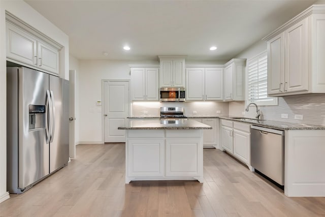 kitchen featuring decorative backsplash, light wood-type flooring, appliances with stainless steel finishes, and a sink