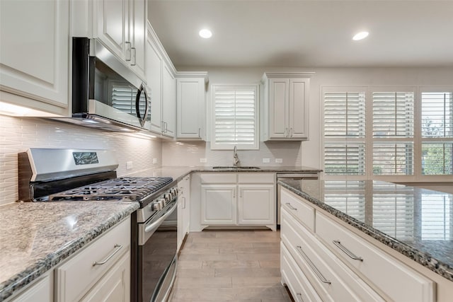 kitchen with decorative backsplash, a healthy amount of sunlight, appliances with stainless steel finishes, and a sink