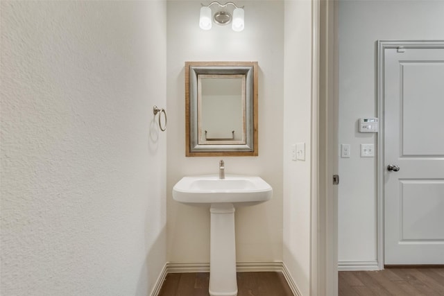 bathroom featuring a sink, baseboards, and wood finished floors