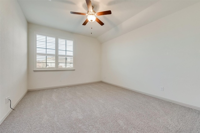 empty room with light colored carpet, baseboards, ceiling fan, and vaulted ceiling