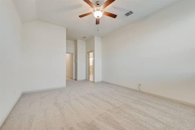 spare room with visible vents, a ceiling fan, baseboards, light colored carpet, and vaulted ceiling