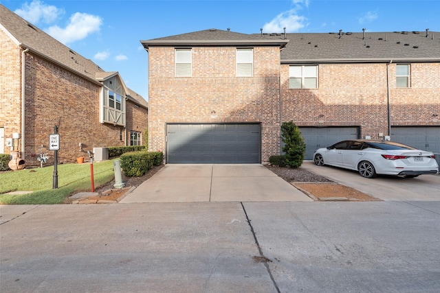 view of property featuring cooling unit, roof with shingles, concrete driveway, a garage, and brick siding