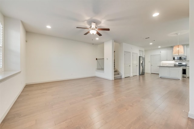 unfurnished living room with stairway, baseboards, light wood finished floors, recessed lighting, and ceiling fan