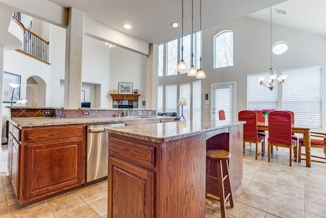 kitchen featuring a center island, a breakfast bar area, brown cabinets, a notable chandelier, and stainless steel dishwasher