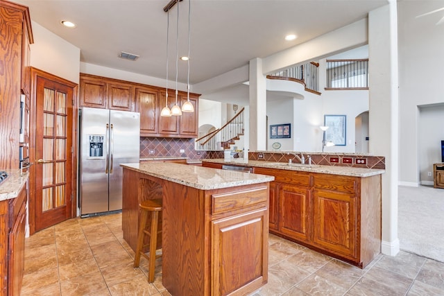 kitchen with brown cabinets, tasteful backsplash, appliances with stainless steel finishes, and a center island