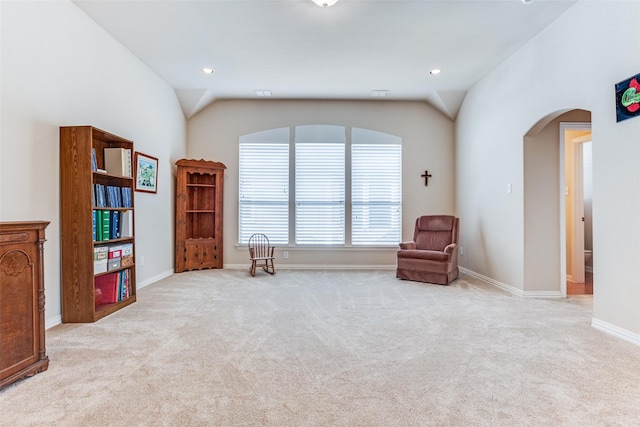 living area with arched walkways, baseboards, carpet, and vaulted ceiling