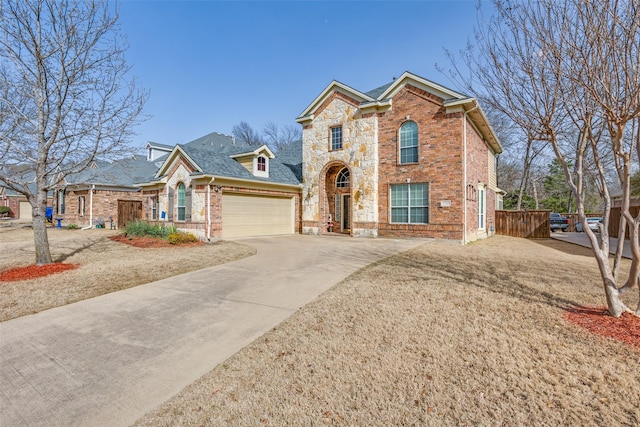 traditional-style home with driveway, an attached garage, brick siding, and stone siding