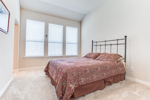 bedroom with vaulted ceiling, multiple windows, baseboards, and carpet floors