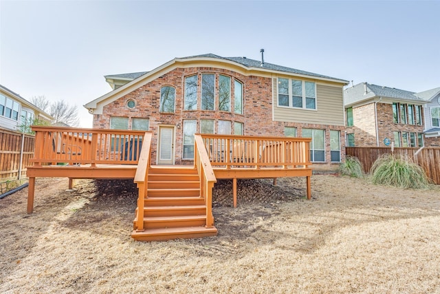 back of house with brick siding, a deck, and fence