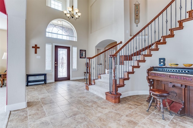 foyer entrance with stairway, plenty of natural light, baseboards, and a chandelier