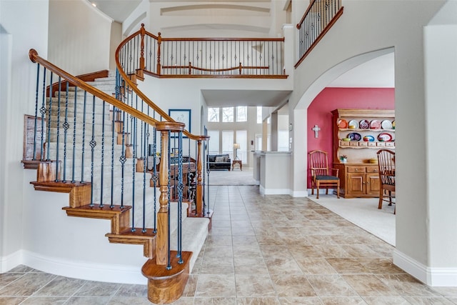 foyer featuring arched walkways, a high ceiling, and baseboards