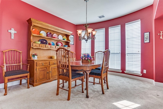 dining room featuring visible vents, baseboards, light colored carpet, and a chandelier