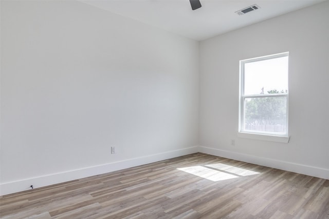 spare room with light wood finished floors, visible vents, ceiling fan, and baseboards