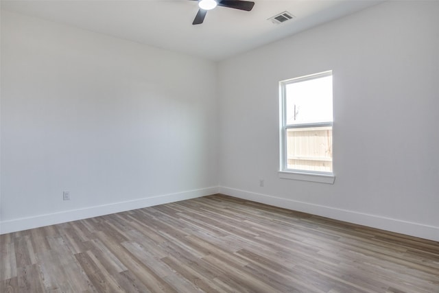 empty room featuring ceiling fan, wood finished floors, visible vents, and baseboards