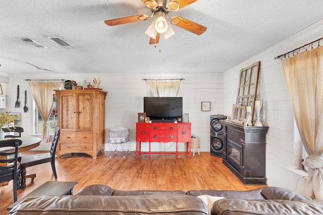 living area featuring visible vents, a textured ceiling, ceiling fan, and wood finished floors