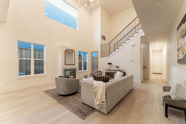 living area featuring a glass covered fireplace, light wood-style flooring, baseboards, and visible vents