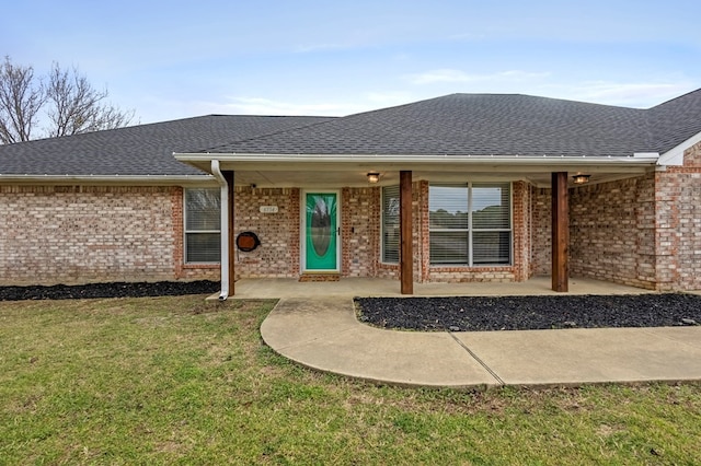 exterior space with a yard, brick siding, and roof with shingles