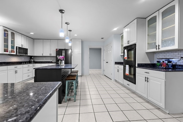 kitchen with light tile patterned floors, hanging light fixtures, white cabinets, appliances with stainless steel finishes, and backsplash