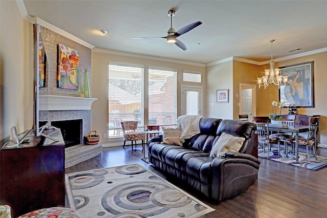 living room featuring visible vents, ornamental molding, ceiling fan with notable chandelier, wood finished floors, and a fireplace