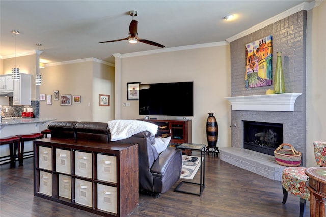 living room featuring ornamental molding, a fireplace, ceiling fan, and dark wood-style flooring