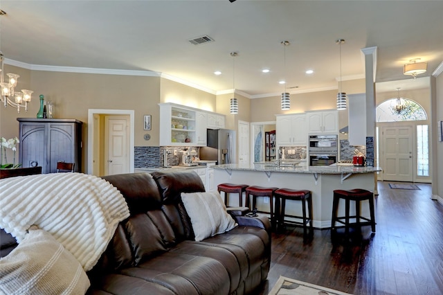 living area with dark wood-style floors, visible vents, an inviting chandelier, and ornamental molding